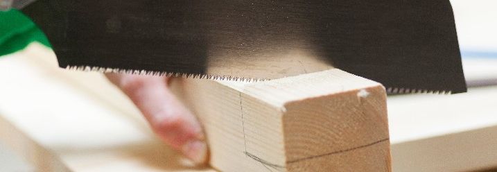 Mann sägt Holzstück mit Japansäge.